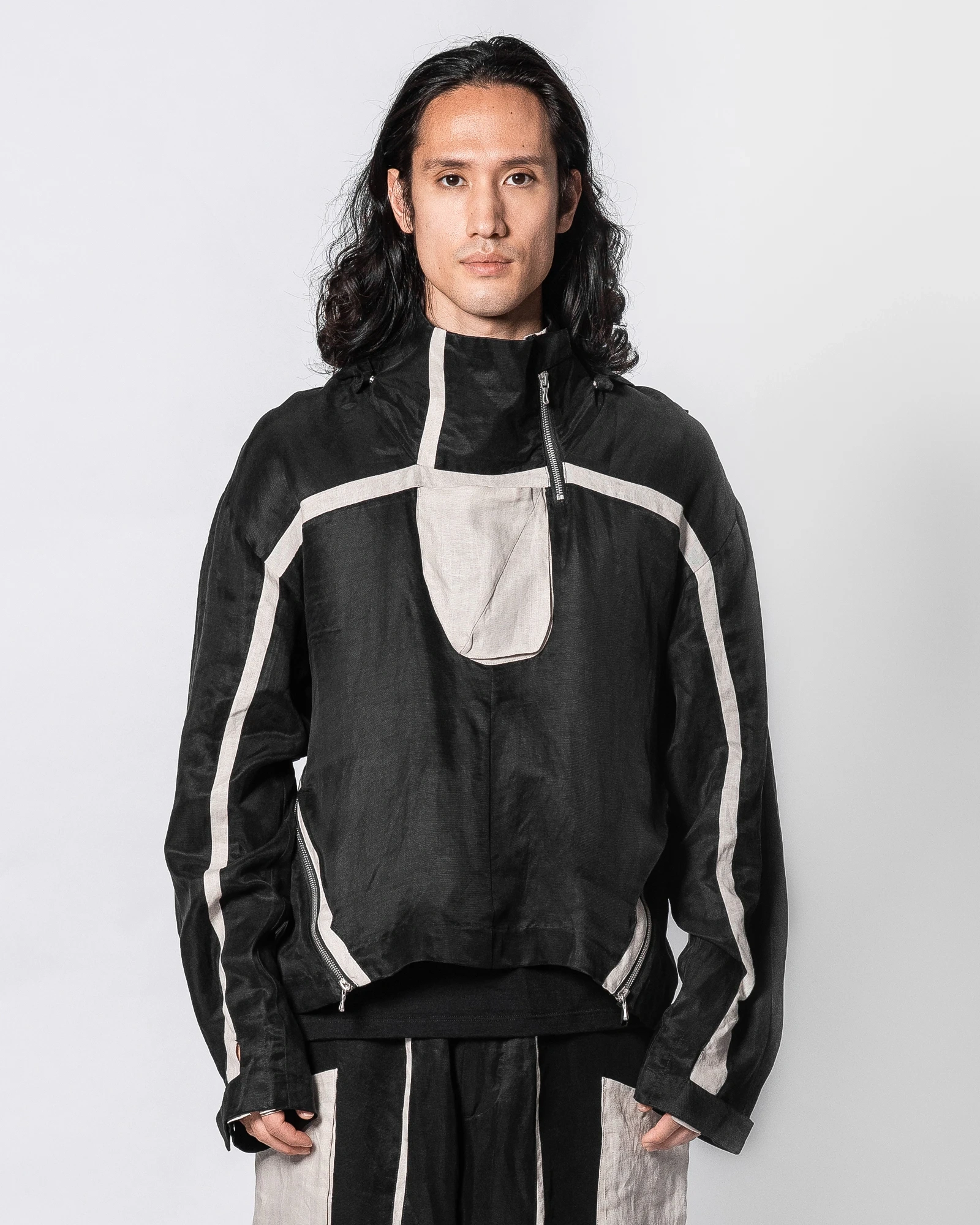 Product shot of a model wearing the black and sand Atrius Anorak